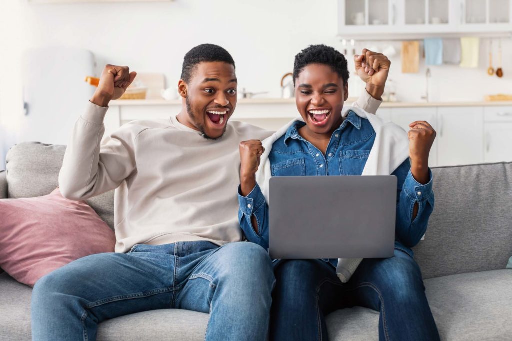 Couple celebrating while looking at their laptop
